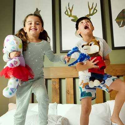 Two kids jumping on a bed in a Great Wolf Lodge Suite